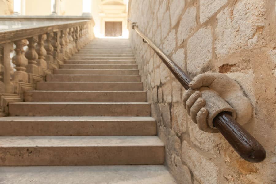 Stone hand holding stairway railing in the Rector’s Palace in Dubrovnik, Croatia.